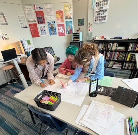 This is an image of three students working at a table together on an assignment.