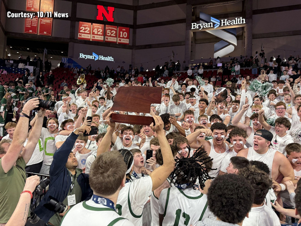 A large number of Southwest High School students celebrate with the school's boys basketball team at Pinnacle Bank Arena. Basketball players are holding the state championship trophy in the air.