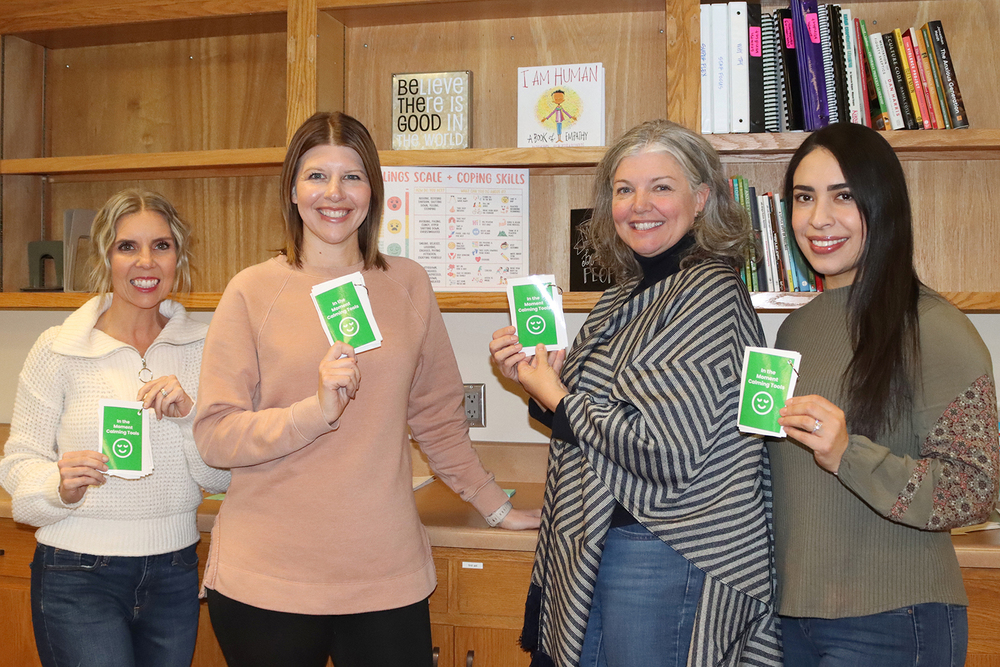 From left, Amber Cownie, Kate Pittack, Shauna Green and Liseth Herrera smile in their office with flashcards containing new In the Moment calming tools. The four school counselors are standing in front of shelves that contain many items with encouraging phrases. Many students are using the calming tools this year to remain composed in stressful situations.