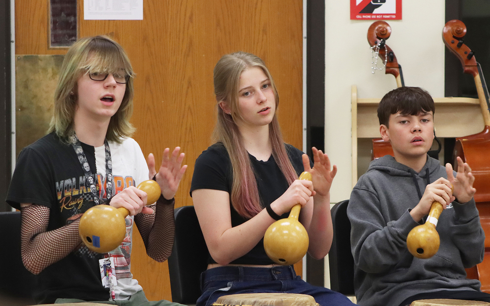 Three Lincoln High students play shaker instruments during the World Music Drumming class. The row includes a boy, a girl and a boy.