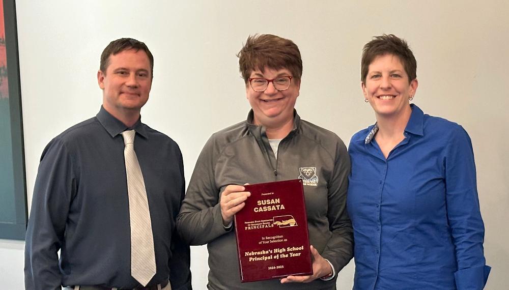 A woman holds an award plaque that reads, SUSAN CASSATA PRINCIPAL In Recognition of Your Selection as a Nebraska Exemplary Principal.
