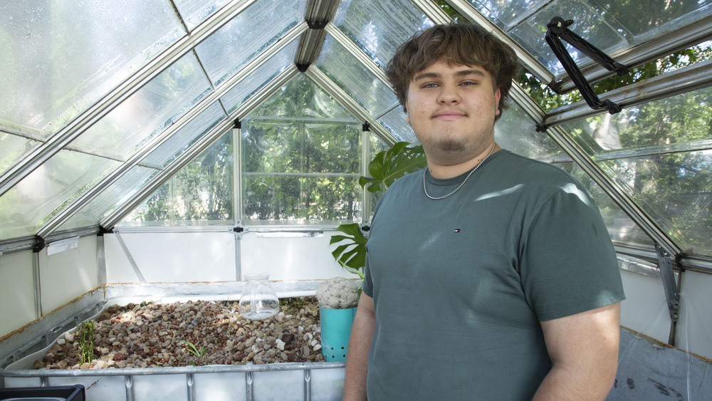 Science Focus Program student Emilio stands in greenhouse.