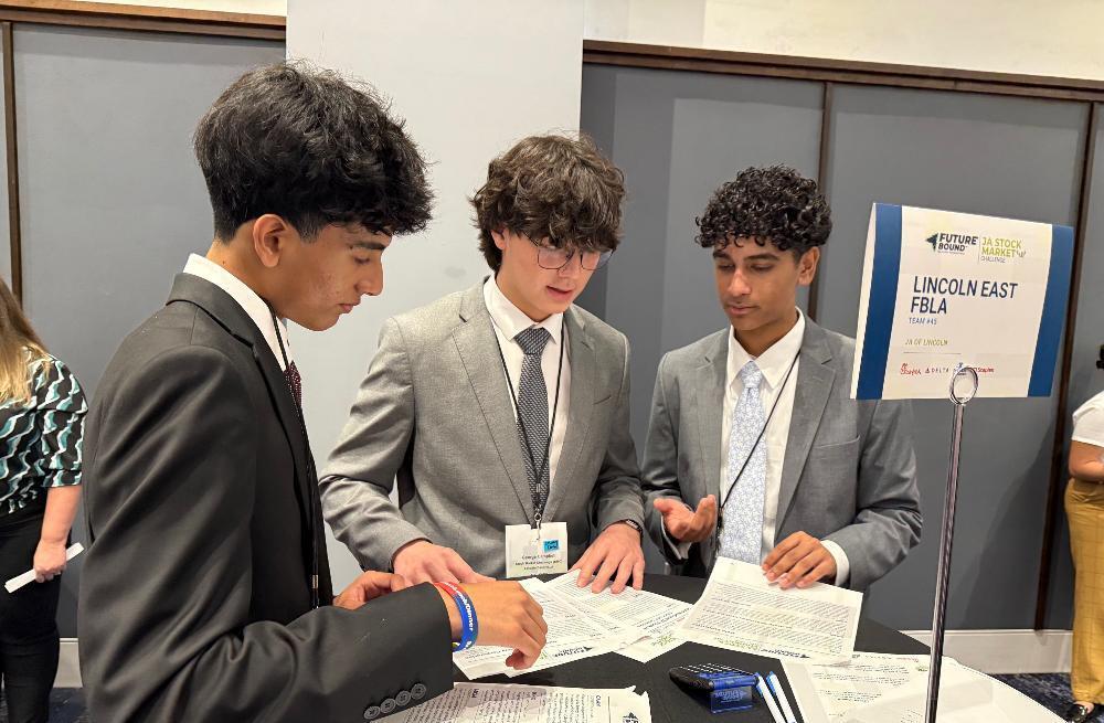 From left, East High School students Ronav, George and Anish look over pieces of paper that detail their investment plans for the Junior Achievement Stock Market Challenge. They finished eighth out of 45 teams at the national contest in Atlanta.