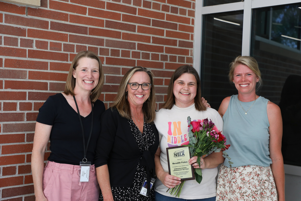 From left, Joy Harvey, Christine Haeffner, Meredith Fickes and Emily Jacobs smile outside Mickle Middle School. Fickes is holding a bouquet of flowers and her state library award.