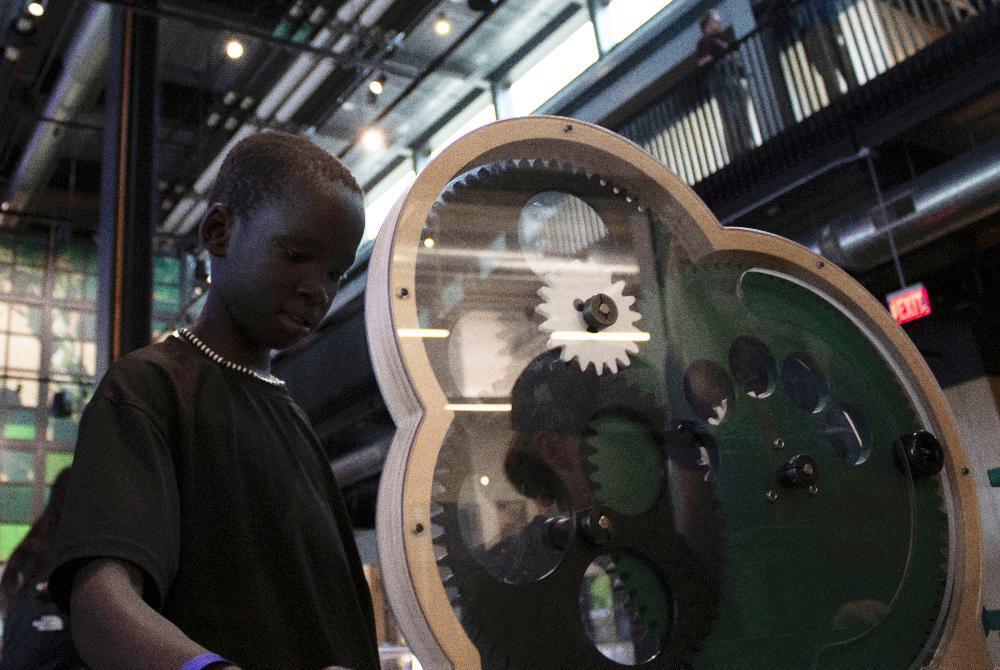 A Culler Middle School student explores a large group of circular gears as part of an exhibit at the Kiewit Luminarium in Omaha.