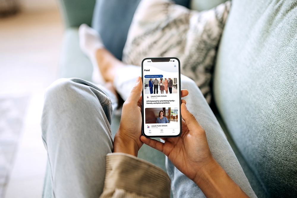 A cell phone with the LPS app in the hand of a woman sitting on the couch.