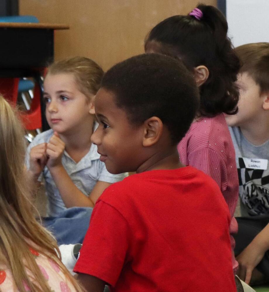 A kindergarten student in Emily Mujica's class at Randolph Elementary School sits in a circle with her classmates on the first day of school.