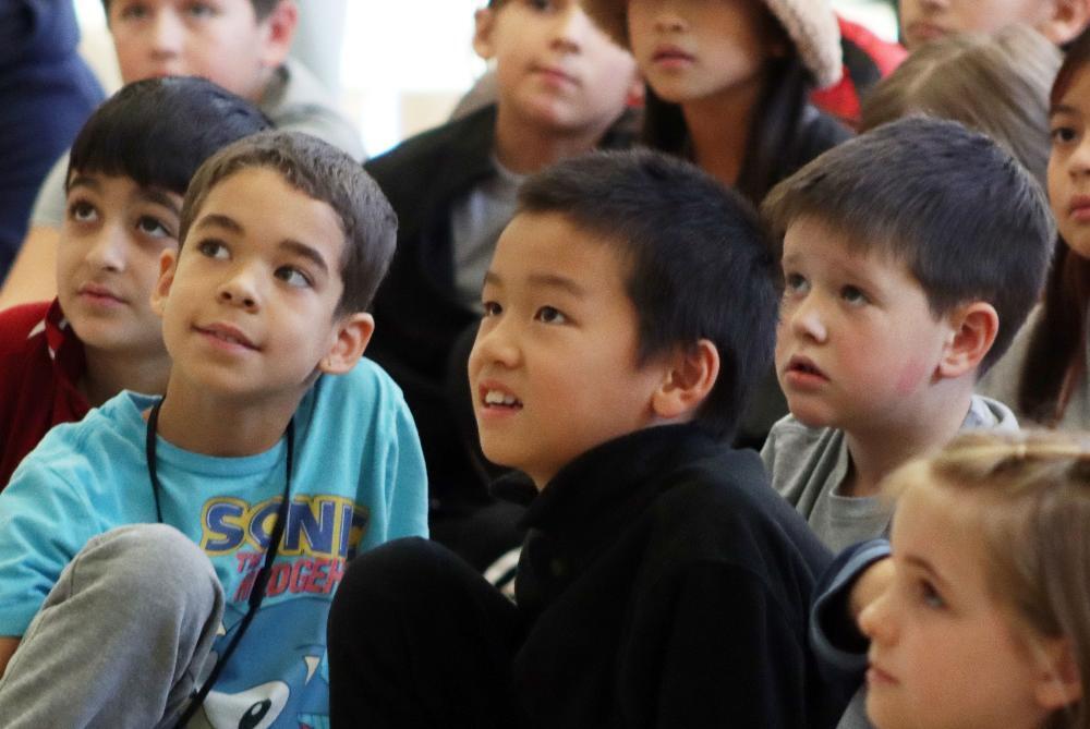 Kooser Elementary School students gaze up at four University of Nebraska-Lincoln student-athletes at a visit to their school.