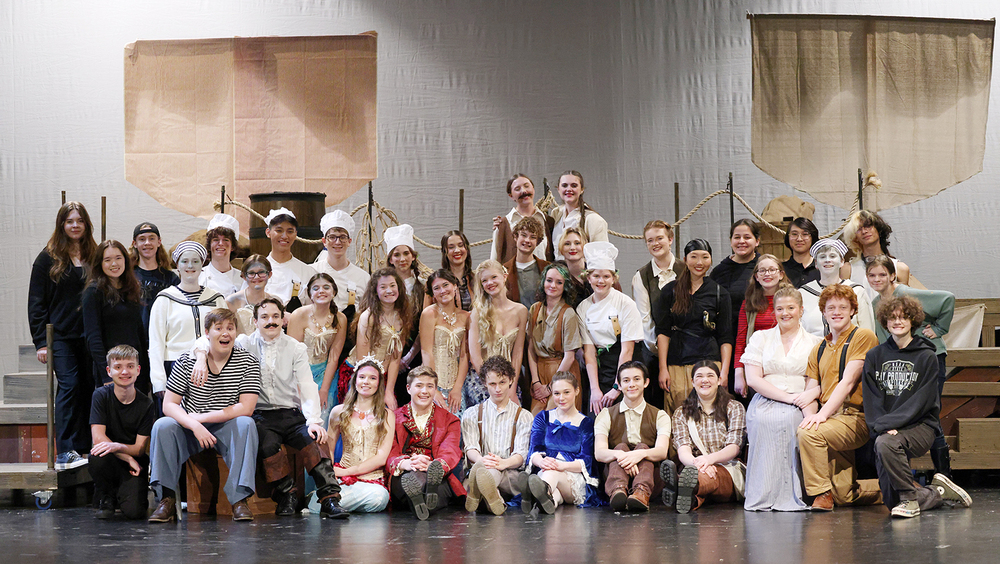 More than 30 East High School students are gathered in a group picture on the auditorium stage. They are in four rows and are wearing costumes from their one-act play production.