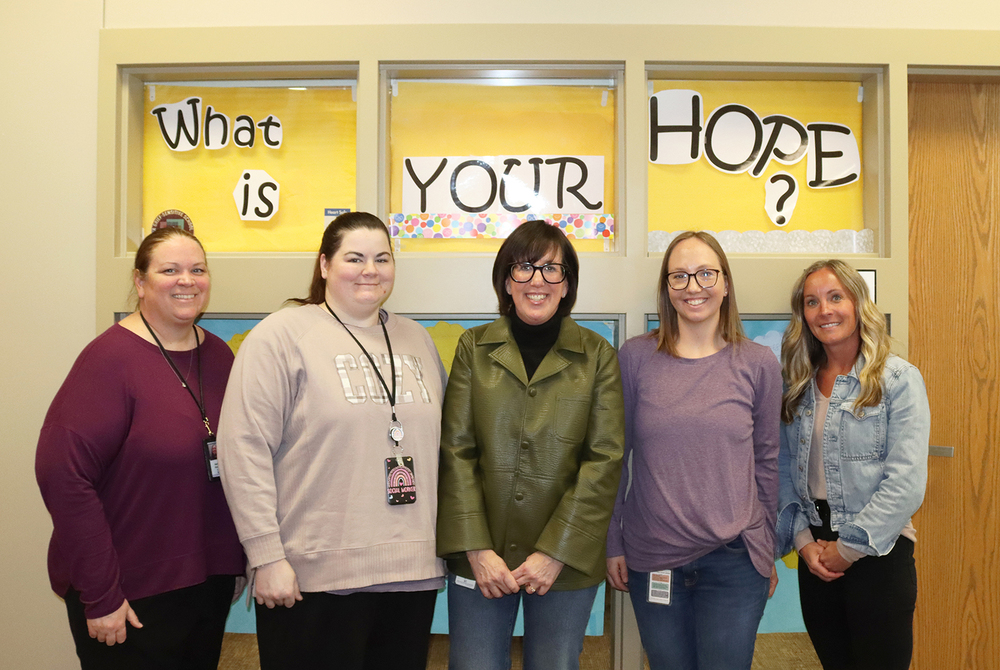 School social workers Becca Rivers, Danae Hyde and Heather Bock are helping students across Lincoln through programs funded by two new federal grants. They are primarily assisting at the Student Support Program, LPS Transition Program and Pathfinder Education Program. From left, LPS Mental Health Coordinator Andrea Phillips, Bock, Rivers, Hyde and Student Support Program Coordinator Ashley Dotson stand under a sign that says, "What is Your Hope?" in an office window.