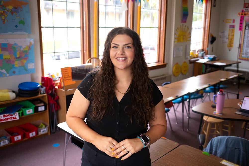 A woman standing in a classroom wearing a black shirt.