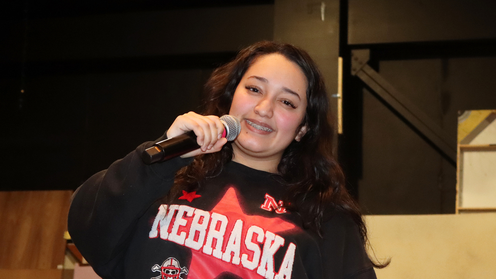 Southwest High School senior Nataly smiles as she holds a microphone near her mouth with her right hand.