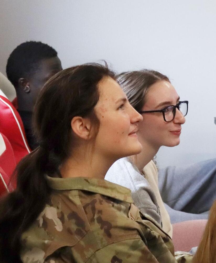 Northeast High School junior Alexi is smiling in the center of the photo, sitting in a chair at a Northeast High School STEM event with a local company representative.