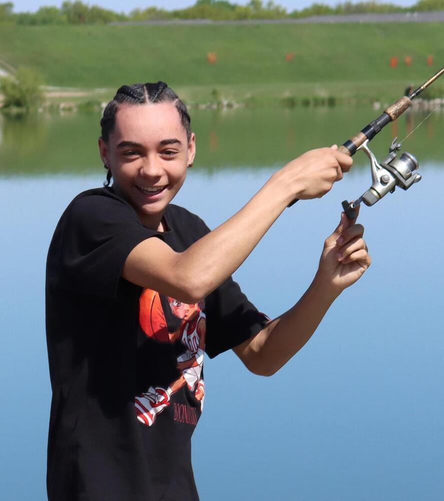 A Yankee Hill student smiles as he holds his fishing rod and reel at Holmes Lake.