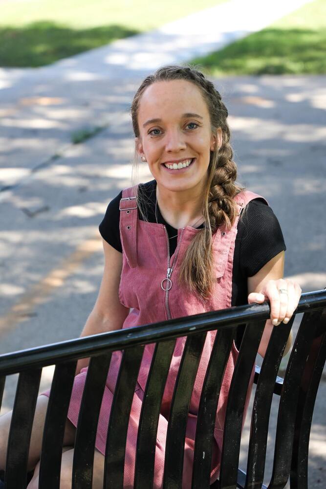 A woman sitting on a bench, wearing a black shirt.