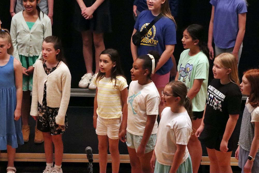 Several rows of fifth grade students sing together on a stage at Irving Middle School during the 2025 LPS Summer Choral Music Camp.