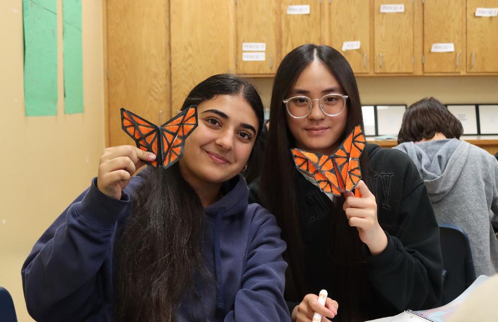 Two eighth graders in Jillian Schernikau's Spanish I class smile with their origami butterflies. They are at Schoo Middle School.