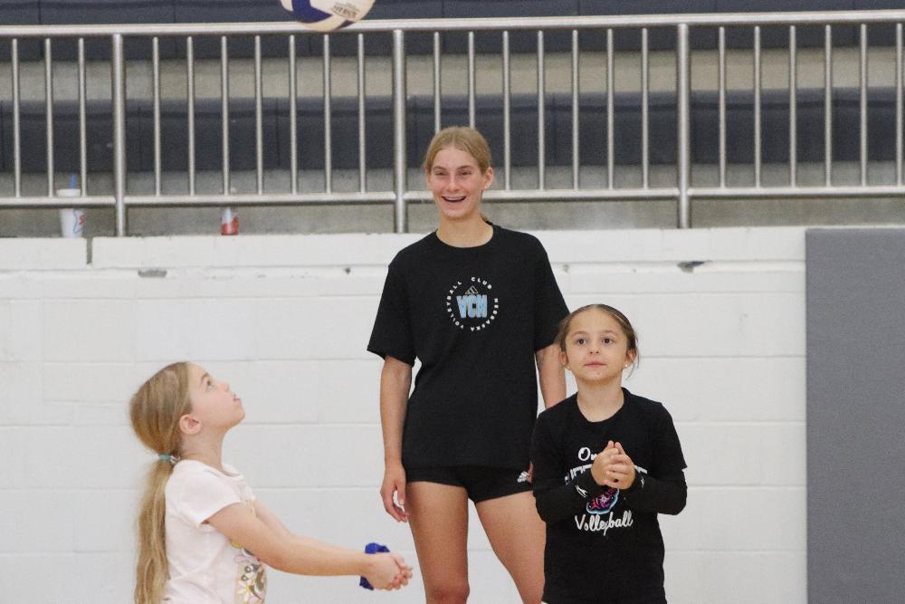 Northwest High School student Lauren smiles as she watches two younger children practice volleyball skills in Northwest's gym during a team camp.