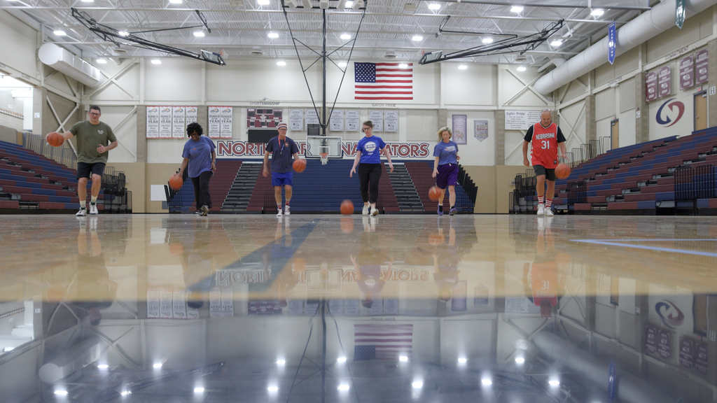 Six members of the Executive Team dribbling basketballs down the gym floor at North Star.