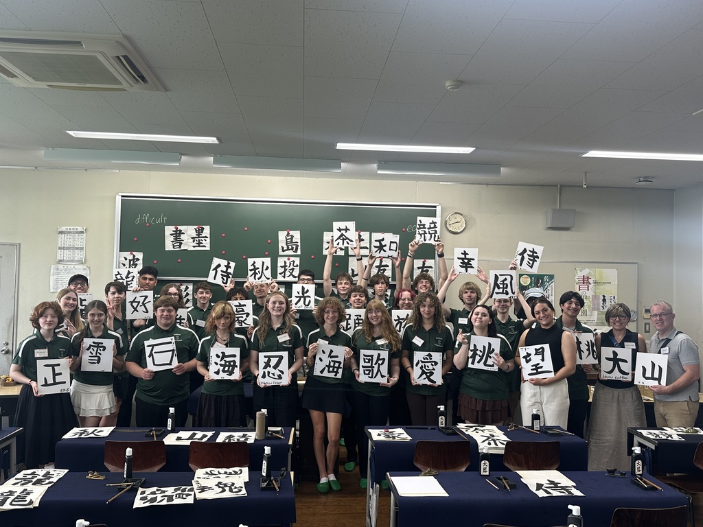 A group of students with signs in Japanese writing