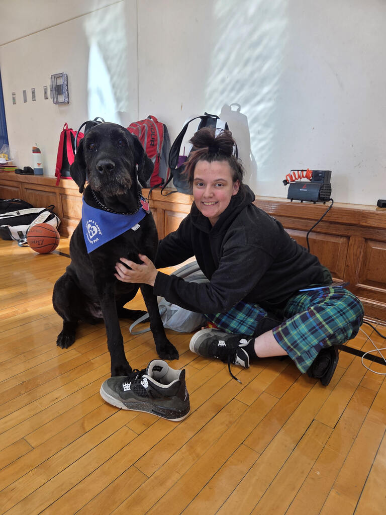 A student poses with the school therapy dog