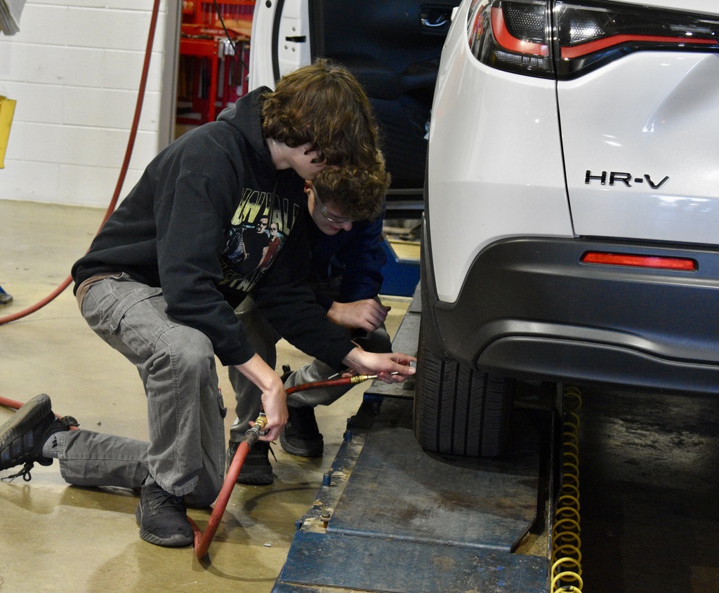 students filling a car tire with air