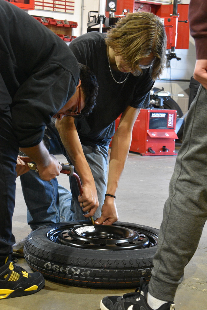 students working to fill a tire