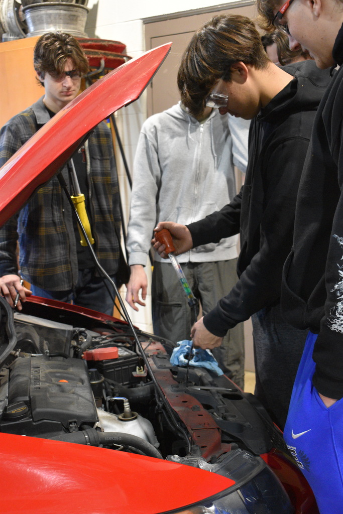 Students checking under the hood of a car
