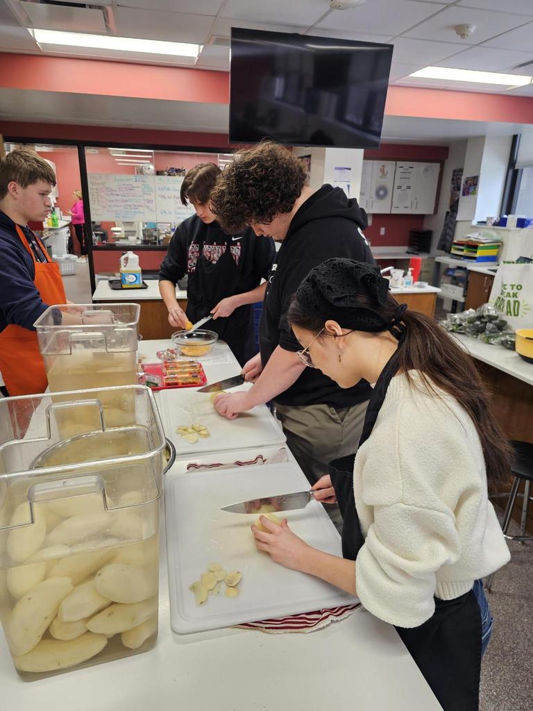students cutting apples and assembling desserts in classroom kitchen