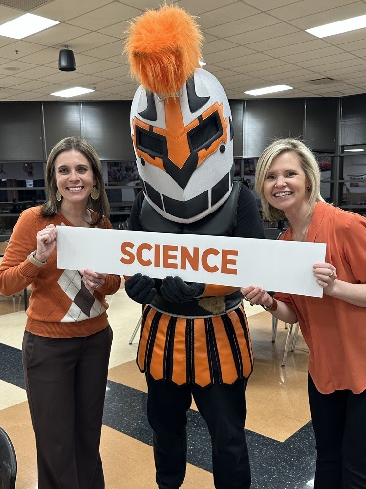 Two teachers posing with the Warrior mascot holding a "Science" sign