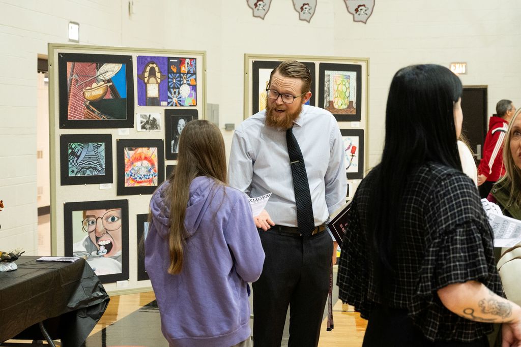A teacher showing a student a brochure about art classes