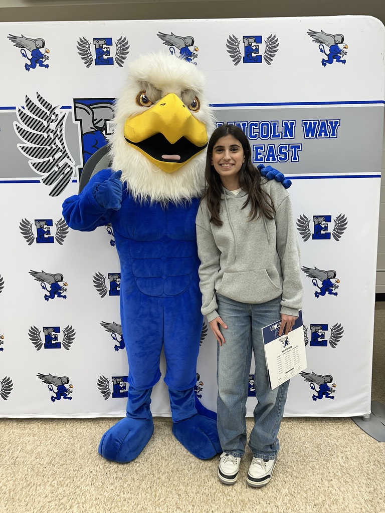 A student posing for a photo with the Griffin mascot