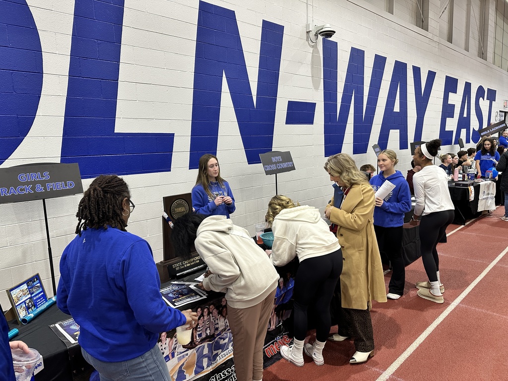 Students and parents standing in front of a table with information about track and field on it