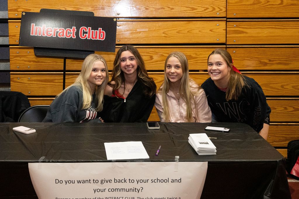 Four students sitting behind a table smiling