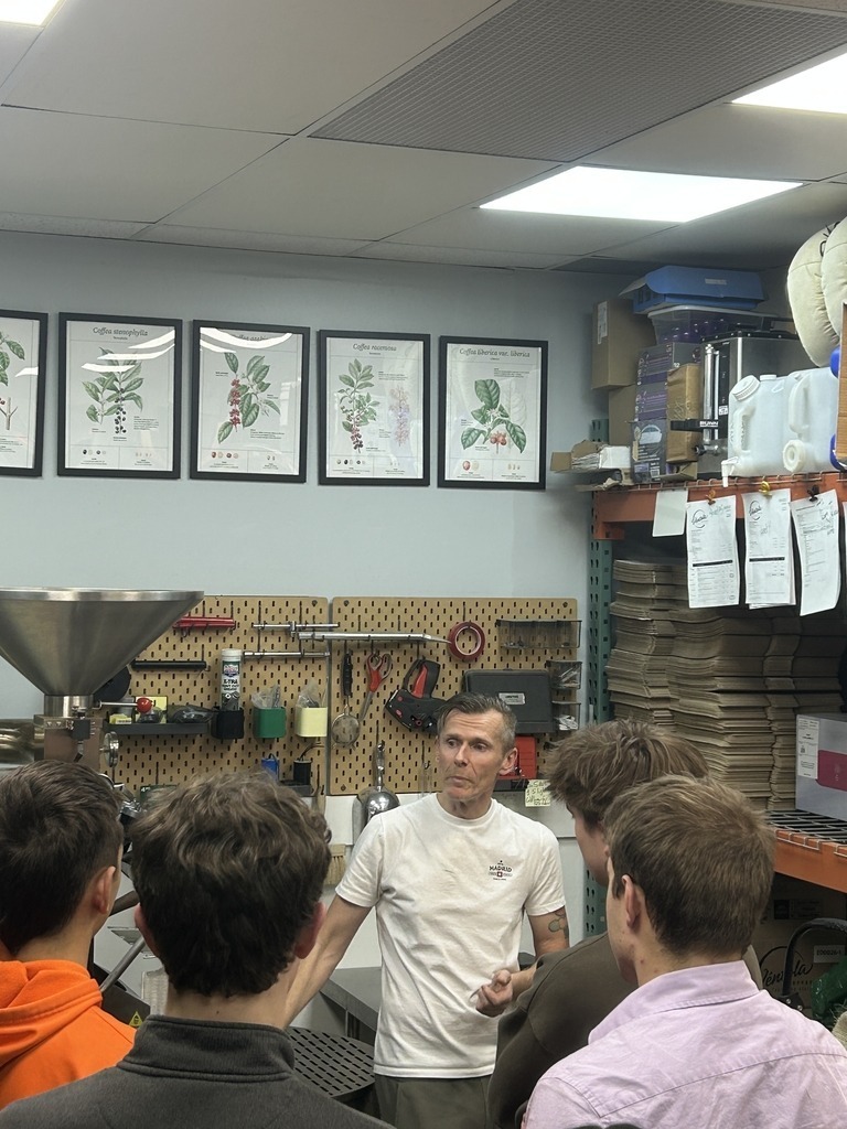 Students gathered around listening to Daniel talk about his business