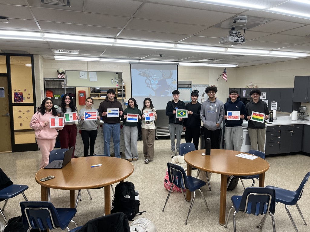 Students in LatinX engaged in small-group creating colored flags representing various Latin countries to contribute to a time capsule project.