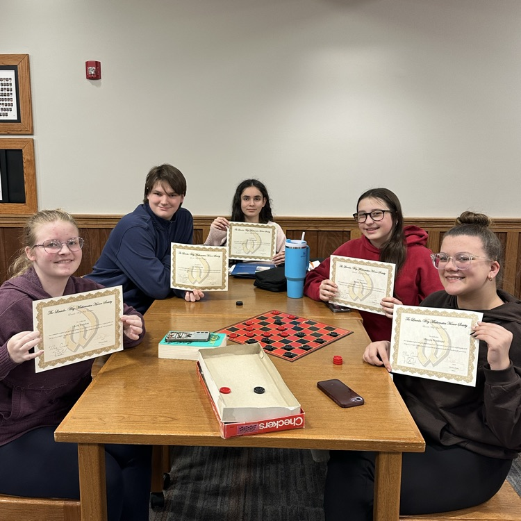 students holding certificates in front board games