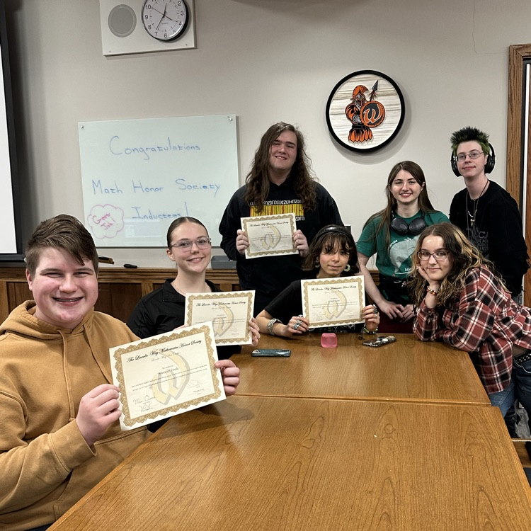 students holding certificates in front of a white board