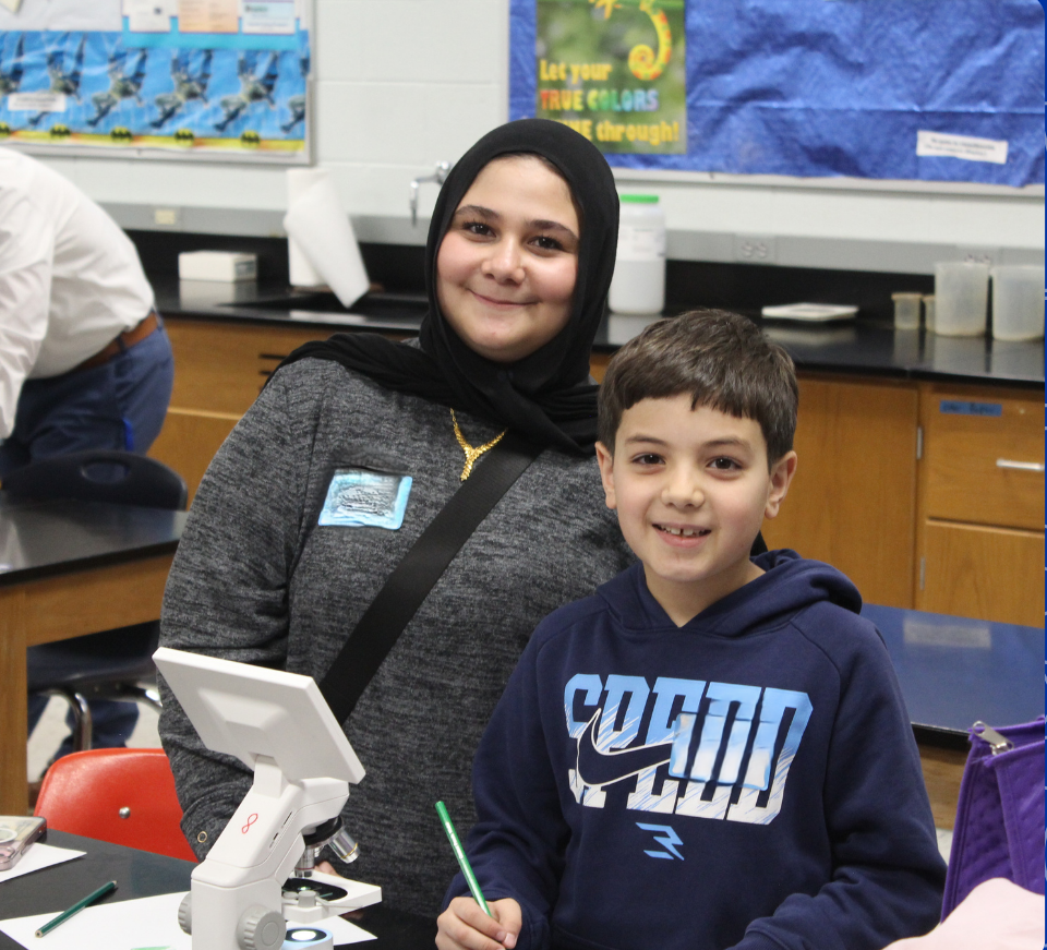 An East student and a child pose for a photo in the science lab.