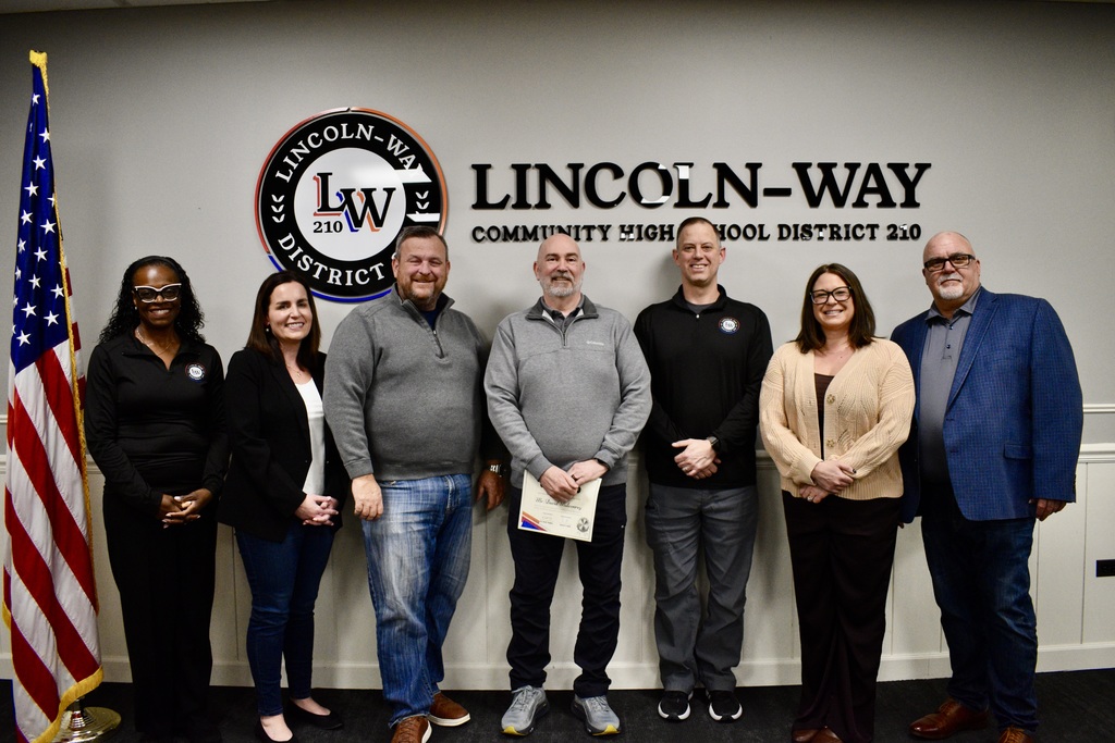 Board members stand in front of a white wall with a "Lincoln-Way" logo, posing for a photo with David Mulconrey.