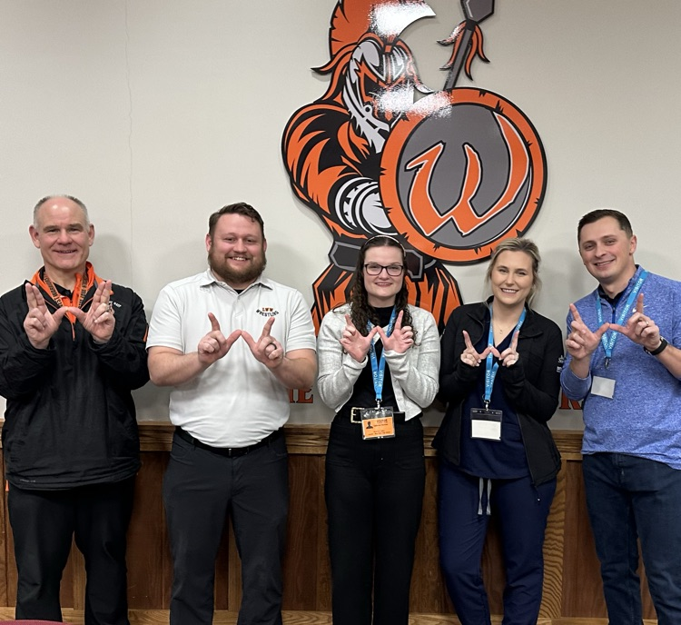 former students in front of the school logo