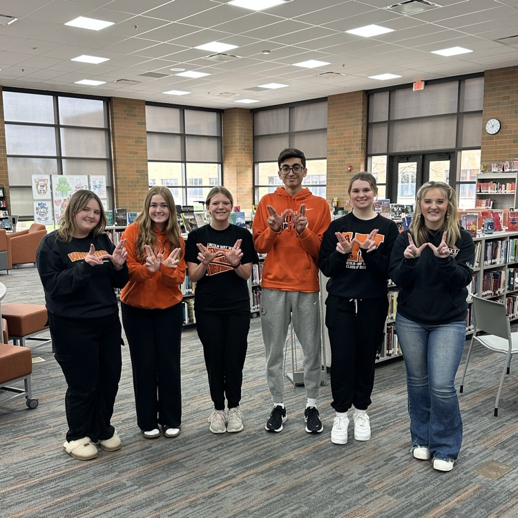 six students standing in a line making Ws and wear LWW spirit wear
