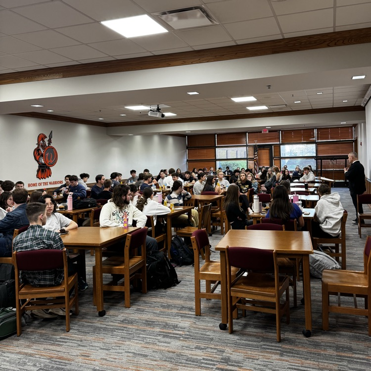 students listening to principal present at breakfast 