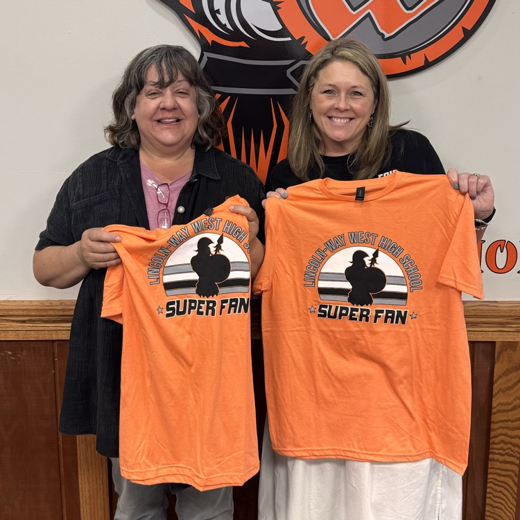 two retiring teachers standing next to each other holding a school super fan shirt 