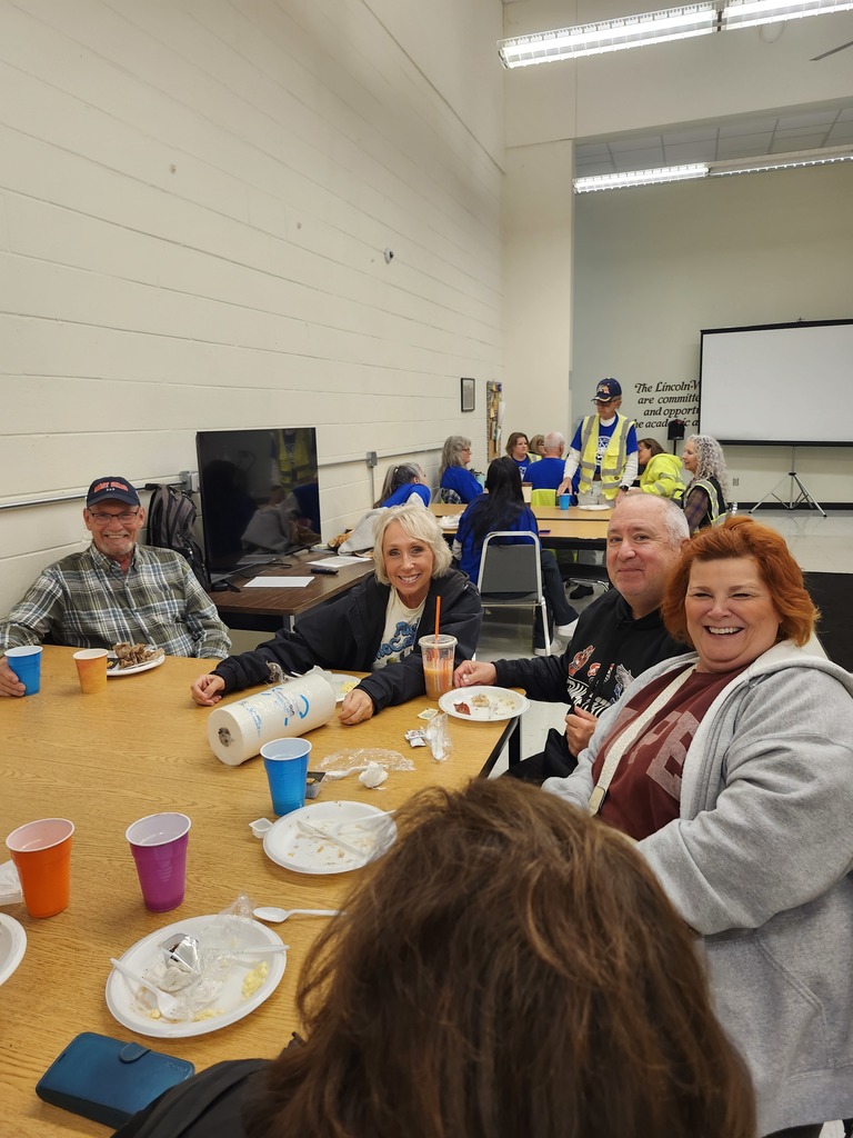 Bus driver appreciation breakfast, drivers sit at a table with food on plates and colorful cups, smiling