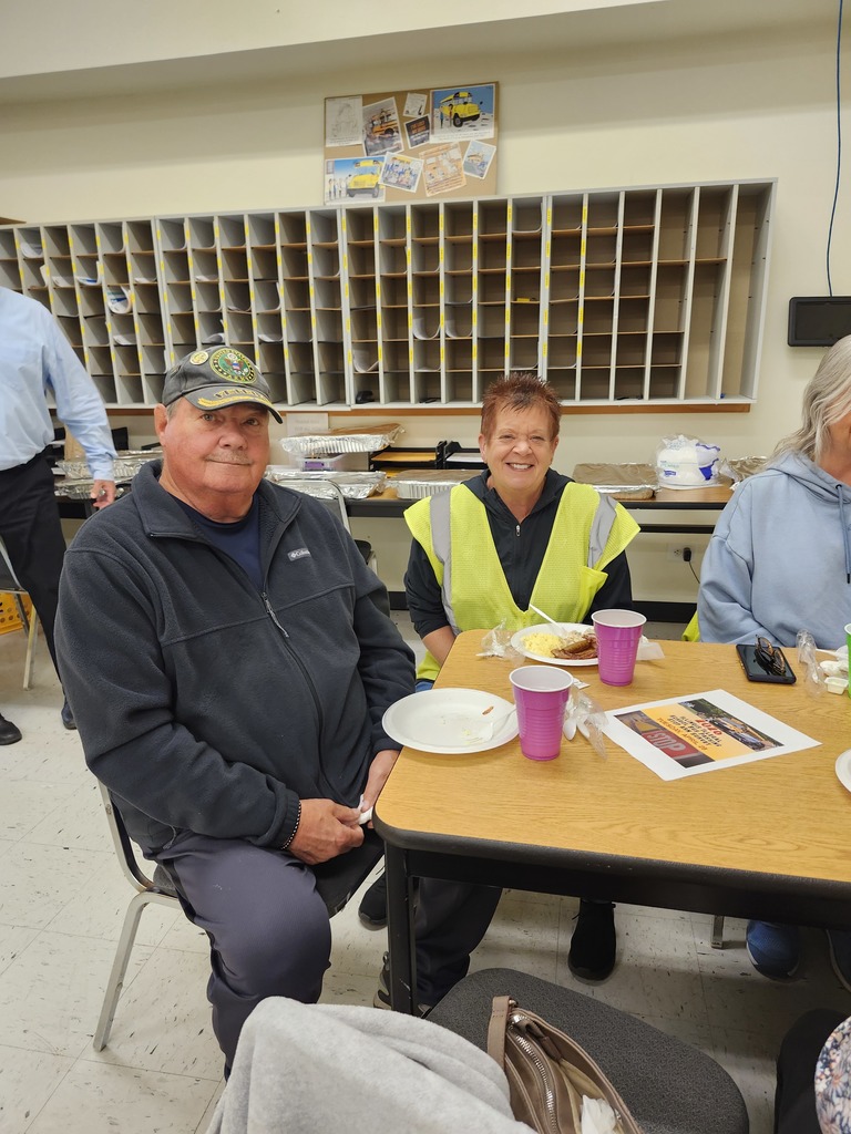 Bus driver appreciation breakfast, drivers sit at a table with food on plates and colorful cups, smiling