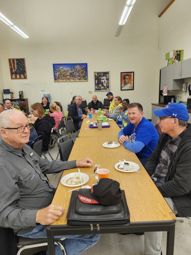 Bus driver appreciation breakfast, drivers sit at a table with food on plates and colorful cups, smiling