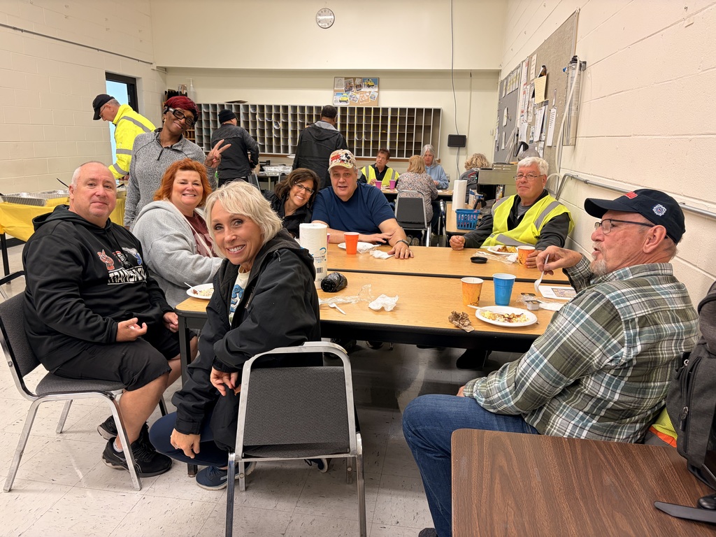 Bus driver appreciation breakfast, drivers sit at a table with food on plates and colorful cups, smiling