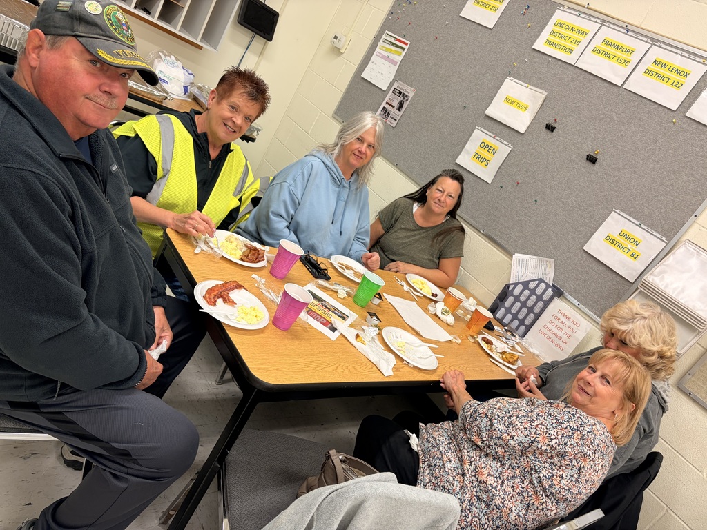 Bus driver appreciation breakfast, drivers sit at a table with food on plates and colorful cups, smiling