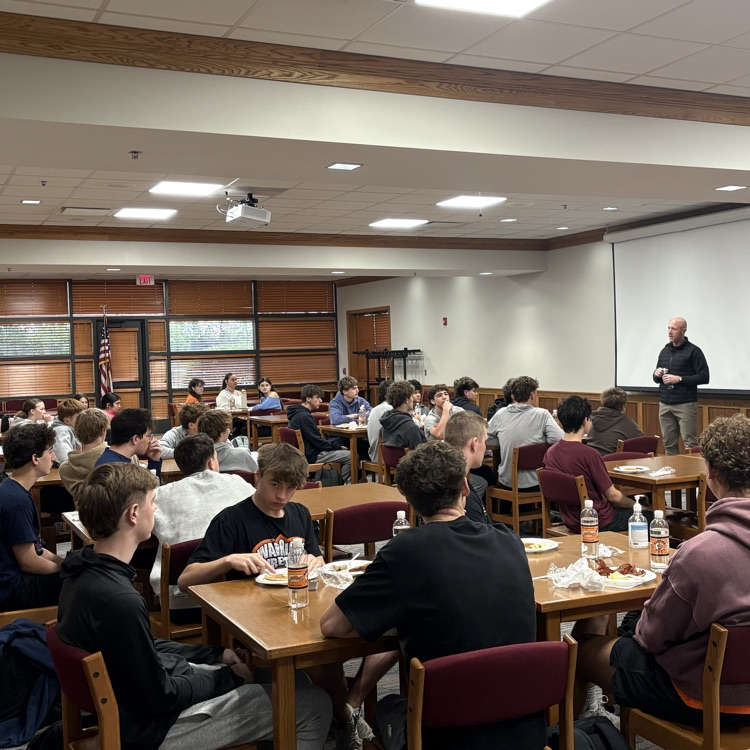 students eating breakfast while listening to guest speaker 